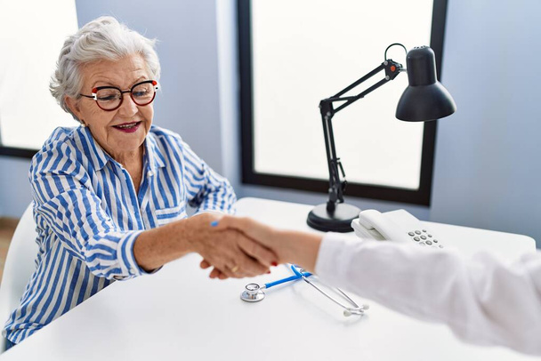 Старшая седовласая пациентка, проходящая медицинскую консультацию, пожимает руку в клинике - Фото, изображение
