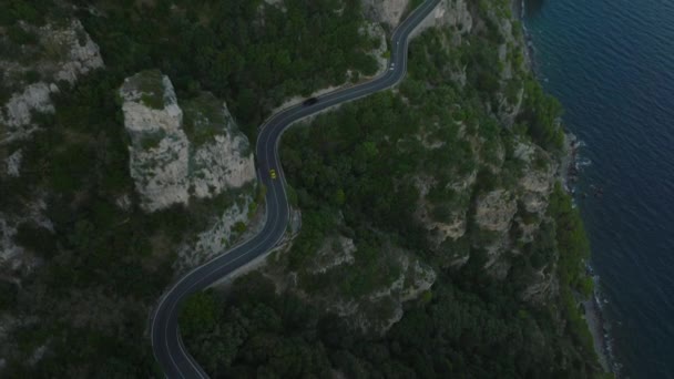 Vista de ángulo alto de los coches que circulan por la ruta panorámica serpenteando en el acantilado de roca por encima de la costa del mar. Inclinado hacia arriba revelando hermosos paisajes. Amalfi, Italia. - Imágenes, Vídeo