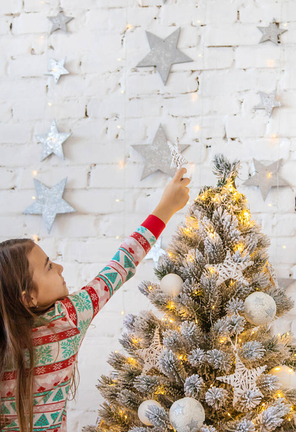 Bir çocuk Noel ağacına bir yıldız asar. Seçici odaklanma. Çocuk. - Fotoğraf, Görsel