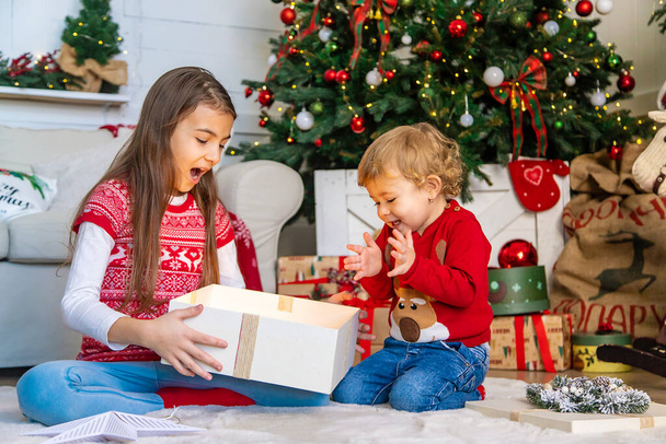I bambini aprono regali di Natale sotto l'albero. Concentrazione selettiva. Ragazzo.. - Foto, immagini