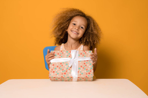 Дитяча дівчинка задоволена хорошим подарунком. Портрет чарівної смішної дівчинки, яка відкриває подарункову коробку і посміхається камері, святкуючи день народження
. - Фото, зображення