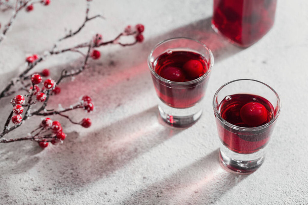 Two glasses of cherry liqueur on white background. Christmas or new year party celebration concept. Winter holidays concept. - Фото, изображение