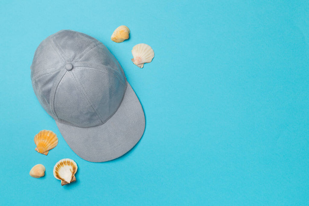 Blue cap and seashells on color background, top view. - 写真・画像