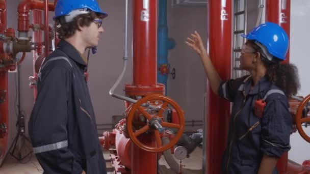 Young woman and man engineer check and examining pipeline and discussion in the factory, mechanic or technician inspector plumber valve and talking together, industrial and maintenance concept. - Felvétel, videó