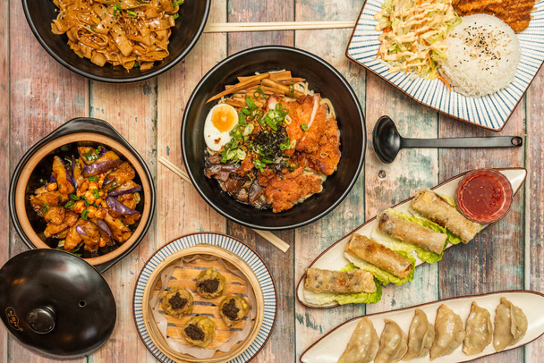 Platos con grandes recetas de comida asiática, fideos con carne de res y salsa de ostras, rollos vietnamitas, fideos con verduras, rameno de pollo, tempura vegetal y gyozas fritas - Foto, imagen