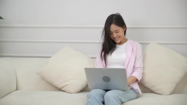 Young asian business woman work from home with laptop computer online to internet on sofa in living room, freelance girl using notebook sitting on couch with comfort and relax, lifestyles concept. - Video