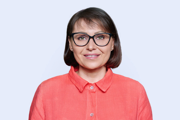Portrait of woman 45 years old looking at camera on white studio background. Smiling middle aged female in glasses wearing red clothes. Age, beauty, profession, lifestyle, mature people concept - Photo, Image