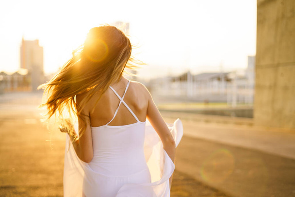 Female adult woman dancing alone outdoors with beautiful golden backlight. - Fotoğraf, Görsel