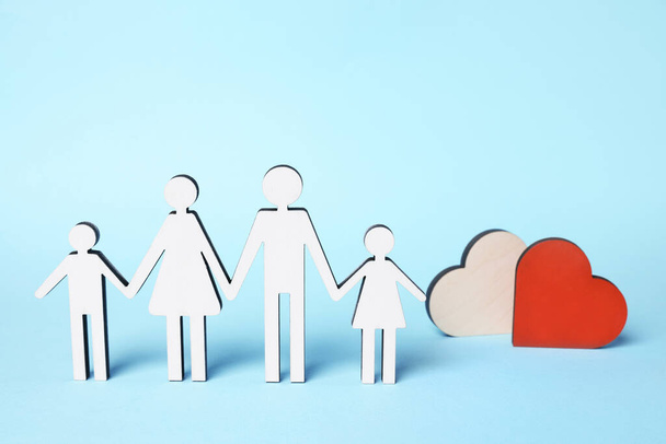 Figures of family stainding near heart on light blue background. Insurance concept - Zdjęcie, obraz