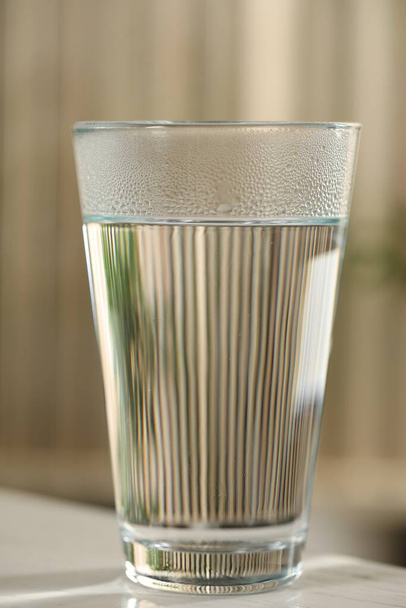 Glass of pure water on white table against blurred background, closeup - Photo, image