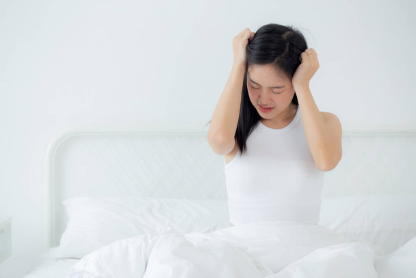 Young asian woman sitting on bed pain headache in the bedroom at home, unhappy female exhaustion and sick headache, anxiety and unwell, dizziness and disorder, medical and health concept. - Fotografie, Obrázek