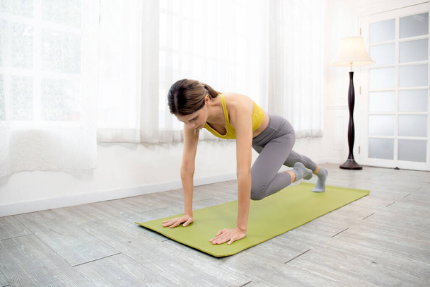 Mooie jonge blanke vrouw oefenen workout oefening met plank stretching spier been en handen terwijl motivatie en vastberadenheid, oefening en sport, een persoon, lichaamsgewicht voor gezondheid concept. - Foto, afbeelding