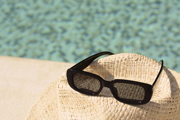 Stylish hat and sunglasses on blurred background, closeup - Fotografie, Obrázek
