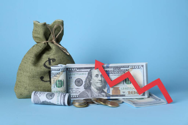 Economic profit. Money bag, coins, banknotes and arrow on light blue background - Photo, Image