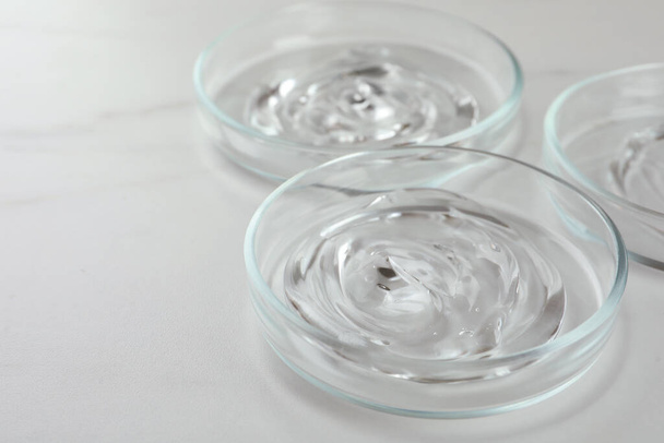 Petri dishes with liquids on white marble table, closeup. Space for text - Fotoğraf, Görsel