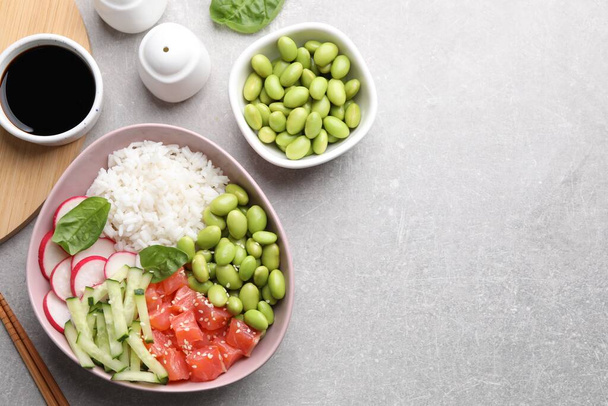 Poke bowl with salmon, edamame beans and vegetables on light grey table, flat lay. Space for text - Photo, image