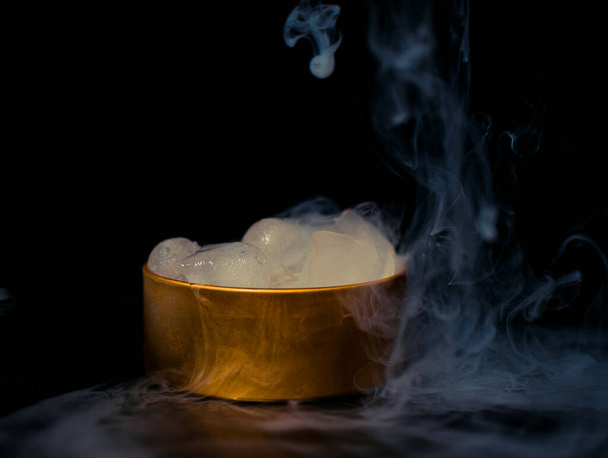Dumanlı altın bir kutuda buz, renkli duman, mavi duman, gri duman, şerbetli buz, lezzetli buz. Koyu arkaplanda boşluk resmi - Fotoğraf, Görsel