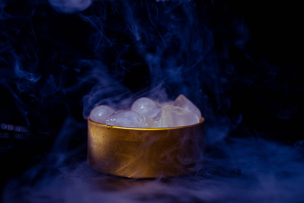 Ice in a golden box with smoke, colorful smoke, blue smoke, gray smoke, ice in syrup, delicious ice. space picture on dark background - Fotó, kép