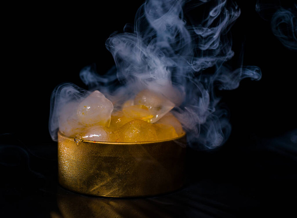 Ice in a golden box with smoke, colorful smoke, blue smoke, gray smoke, ice in syrup, delicious ice. space picture on dark background - 写真・画像