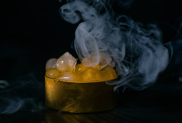 Ice in a golden box with smoke, colorful smoke, blue smoke, gray smoke, ice in syrup, delicious ice. space picture on dark background - Φωτογραφία, εικόνα