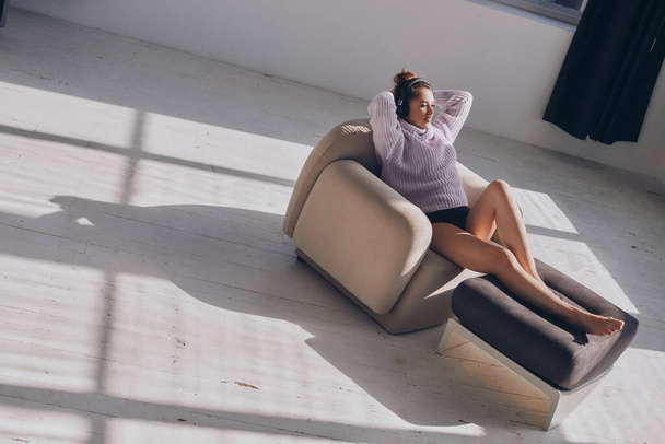 Top view of beautiful young woman in headphones relaxing in comfortable chair - Fotografie, Obrázek