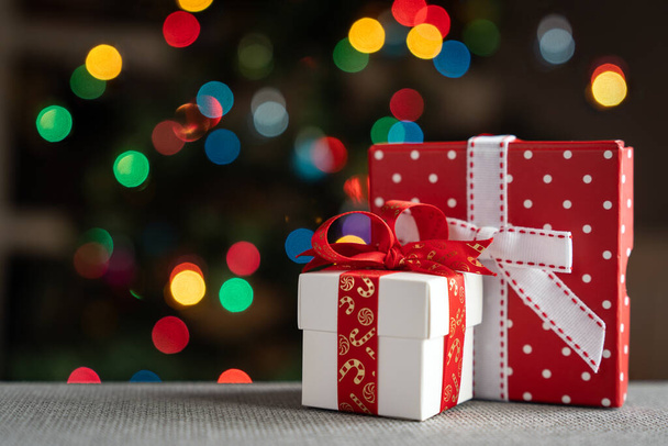 Бело-красные подарочные коробки на фоне рождественской елки - Фото, изображение