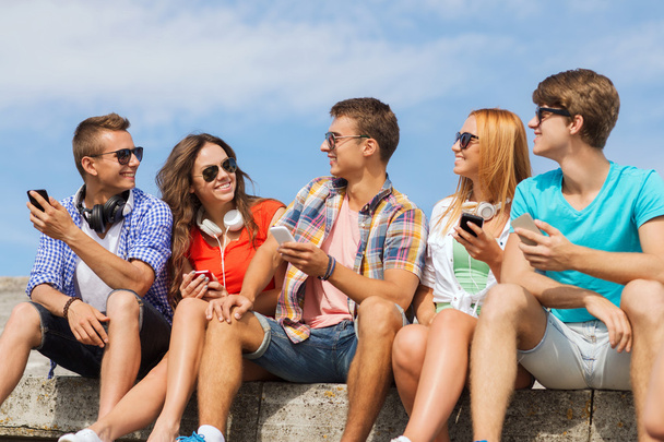 group of smiling friends with smartphones outdoors - Fotó, kép