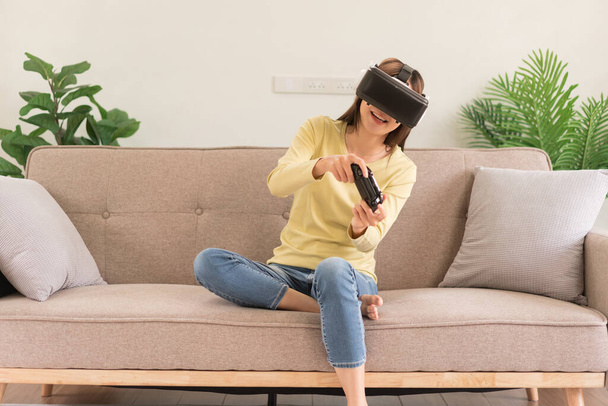 Leisure activities concept, Young woman in VR glasses and controls the joystick to playing games. - Photo, Image