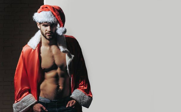 Christmas sexy gay. Young men in santa hat. Santa with muscular body. Handsome sexy santa claus guy on studio background. Sexy Santa Claus - Photo, image