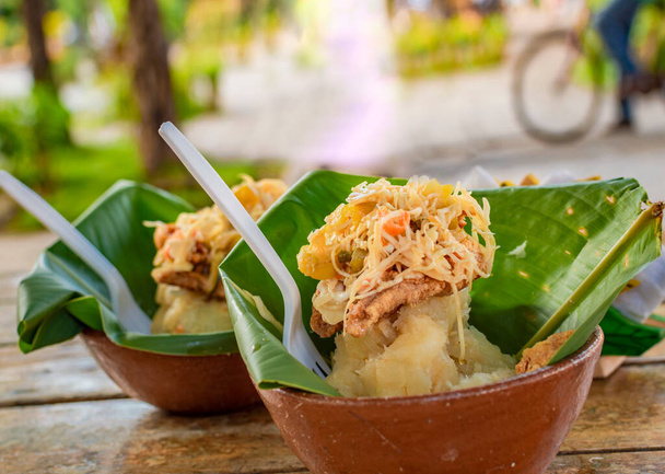 De vitoron typische gerechten van Granada, Nicaragua. Traditionele Vigoron in bananenbladeren geserveerd op een houten tafel. Nicaragua food concept, Close-up van twee krachtpatsers geserveerd op een houten tafel - Foto, afbeelding