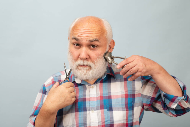 Middle aged hairdresser man. Barber scissors and straight razor hair clipper, Vintage barber shop, shaving. Portrait old bearded man. Vintage barbershop - 写真・画像