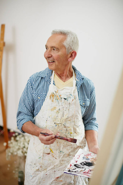 La inspiración existe, pero tiene que encontrarte trabajando. un hombre mayor trabajando en una pintura en casa - Foto, imagen
