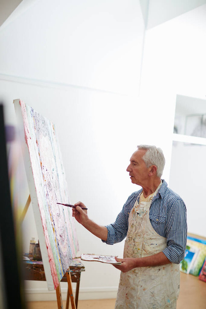 La creatività è una mente selvaggia e un occhio concentrato. un uomo anziano che lavora su un dipinto a casa - Foto, immagini