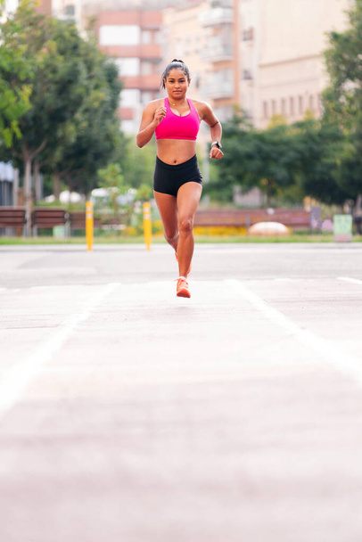 female athlete running on the citys athletics track during her training, urban sport and healthy lifestyle concept, copy space for text - Фото, зображення