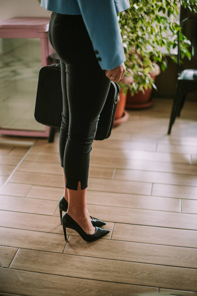 Ділова жінка з чорними підборами і її сумка для ноутбуків стоїть в кафе
 - Фото, зображення