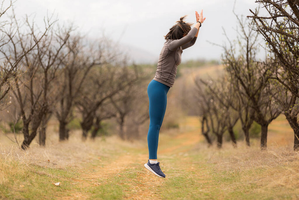 Sport meisje springt en traint in de natuur - Foto, afbeelding