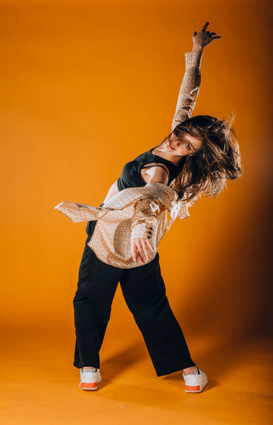 Caucasian female dancer exercising a contemporary dancing on orange wall - Foto, Imagem