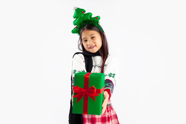 Азійська дитина в зимовому костюмі христмас в головній смузі сосни дарує вам подарунковий ящик з білого фону. Веселого Різдва. - Фото, зображення