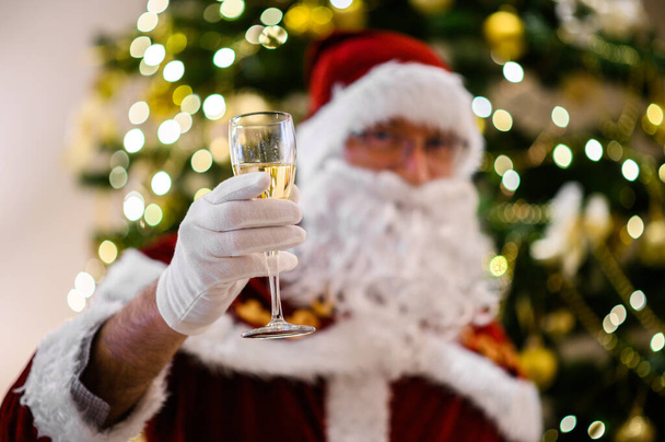 Foto van de gelukkige kerstman in een bril met een glas champagne - Foto, afbeelding