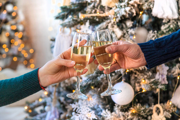 クリスマスツリーの近くで手にシャンパンを持つ男と女。選択的フォーカス。カップル. - 写真・画像