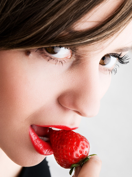 Young woman eating strawberry - Fotografie, Obrázek