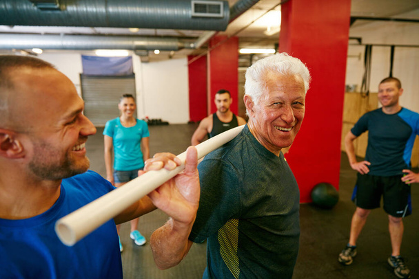 Підвищити стабільність плечей за допомогою труби з ПВХ. старший чоловік робить вправи з трубкою ПВХ за допомогою свого тренера
 - Фото, зображення