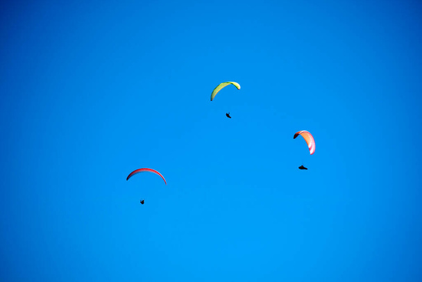 Valokuvausdokumentaatio lennon hetkestä ryhmä varjoliito heitettiin siniselle taivaalle - Valokuva, kuva