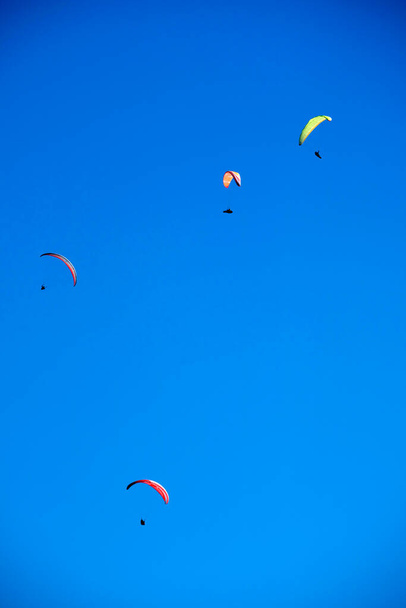 Documentation photographique du moment du vol d'un groupe de parapente jeté dans le ciel bleu - Photo, image