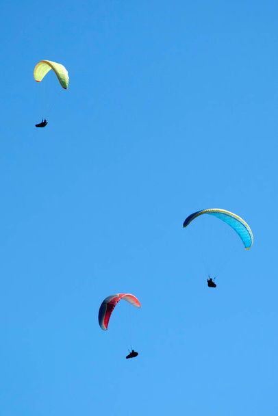 Bir grup paraşütçünün uçtuğu anın fotoğraflı belgeleri mavi gökyüzüne savruldu. - Fotoğraf, Görsel