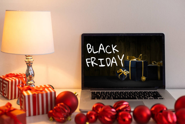 Black Friday shopping concept written in laptops black screen against blurred christmas lights background. - Foto, afbeelding