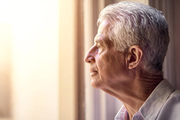 Где мое место в этом мире. вдумчивый пожилой человек, смотрящий в окно дома - Фото, изображение