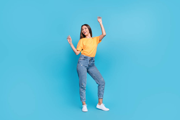 Full length photo of charming excited lady wear yellow t-shirt dancing smiling having fun isolated blue color background. - Fotoğraf, Görsel