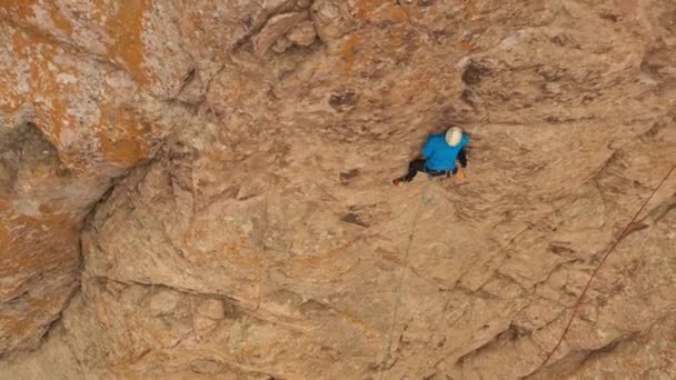 Man Climber Rock Climbing. Útesy v Tamgalii Tas, Kazachstán. Letecký pohled shora dolů. Dron letí bokem - Záběry, video