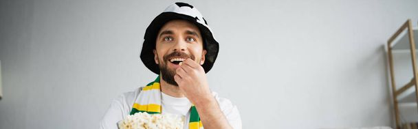 Счастливый спортивный болельщик ест кукурузу и смотрит чемпионат дома, баннер - Фото, изображение